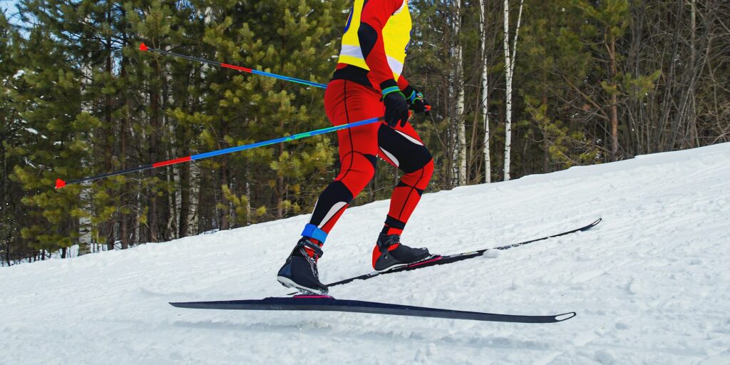 male athlete skier running skiing uphill cross country skiing side view, winter sports competition