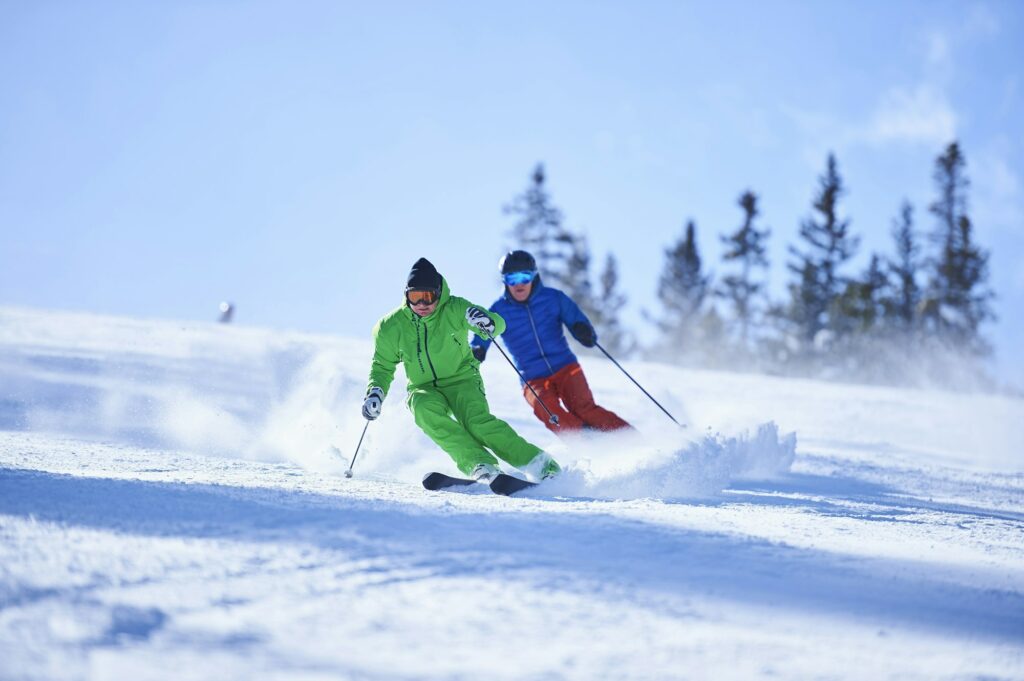 Two men skiing down snow covered ski slope, Aspen, Colorado, USA